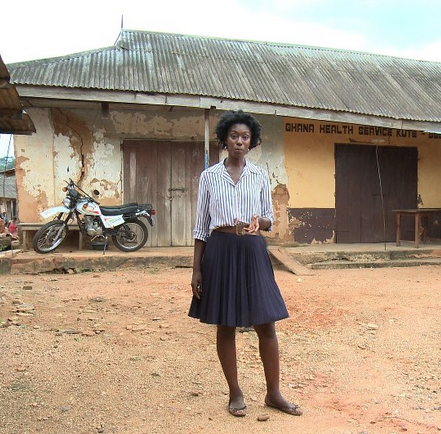 Maternal Health Channel host Ivy in front of the government clinic in Kute Buem.